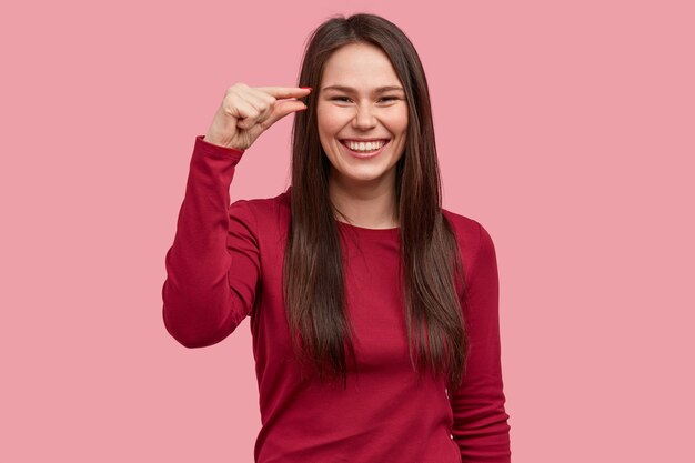 Tiro al coperto di donna sorridente mostra poca quantità di qualcosa, gesti con la mano, essendo di alto spirito