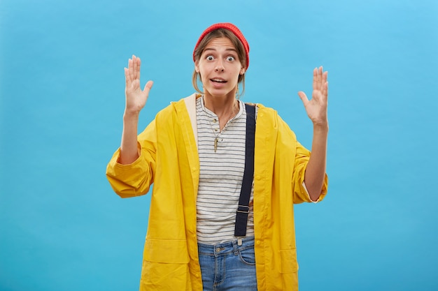 Tiro al coperto di operaio femminile sorpreso che mostra le dimensioni Bella femmina che dimostra le dimensioni di qualcosa di grande o enorme con le mani. Donna stupita che gesturing sopra la parete blu