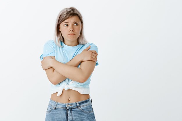 Tiro al coperto di ragazza bionda insicura in posa in studio