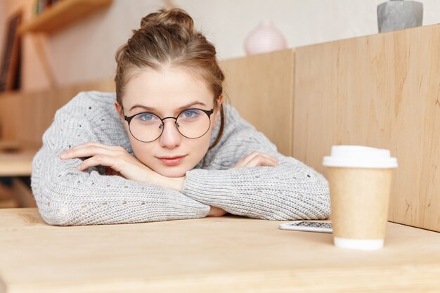 Tiro al coperto di sognante adorabile donna che indossa occhiali rotondi