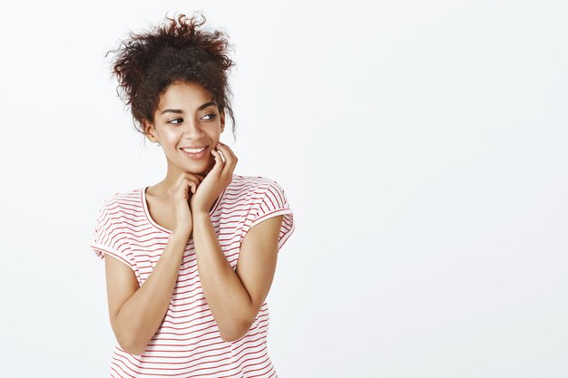 Tiro al coperto di tenera donna con acconciatura afro in posa in studio