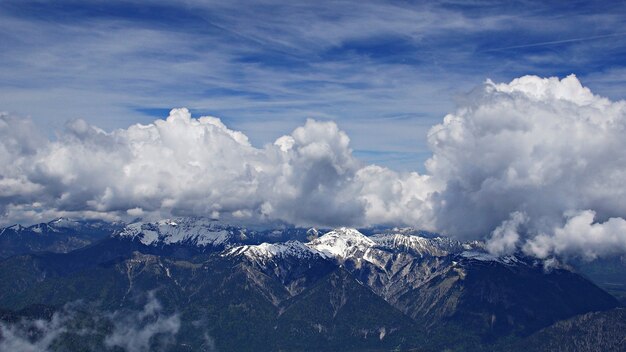 Tiro mozzafiato ad alto angolo di montagne innevate sotto le nuvole e il cielo sullo sfondo