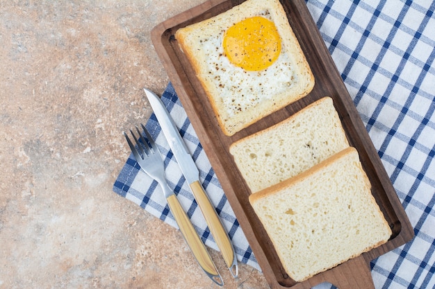 Toast all'uovo con spezie su tavola di legno con posate