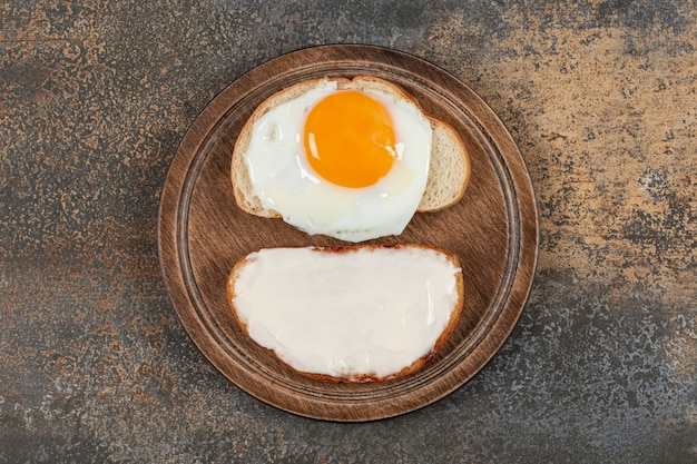 Toast con crema di formaggio e uova su tavola di legno.