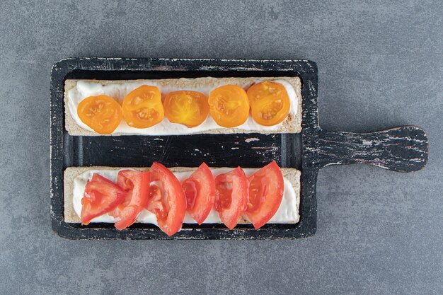 Toast croccanti con pomodori su tavola di legno.