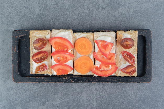 Toast croccanti con pomodori su tavola di legno.