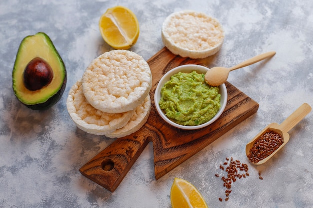 Toast di avocado con pane di riso, fetta di limone, fette di avocado, semi vista dall'alto.