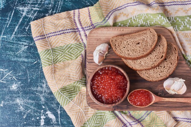 Toast di caviale rosso su tavola di legno.