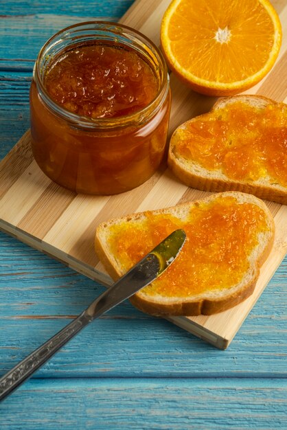 Toast di pane con confettura all'arancia su tavola di legno.