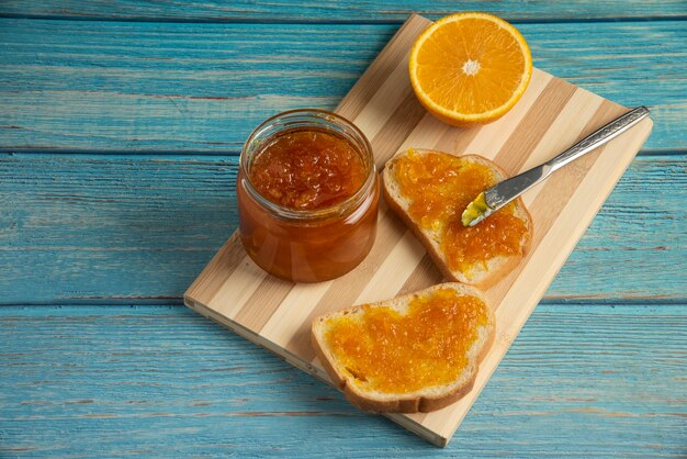 Toast di pane con confettura all'arancia su tavola di legno.