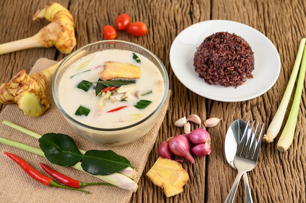 Tom Kha Kai in una ciotola con foglie di lime kaffir, citronella, cipolla rossa, galanga e peperoncino.