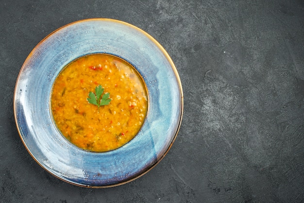 Top primo piano vista piatto di minestra di una zuppa appetitosa con erbe sul tavolo