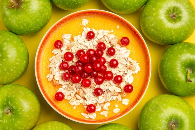 Top vista ravvicinata bacche mele verdi ciotola di farina d'avena frutti di bosco sul tavolo