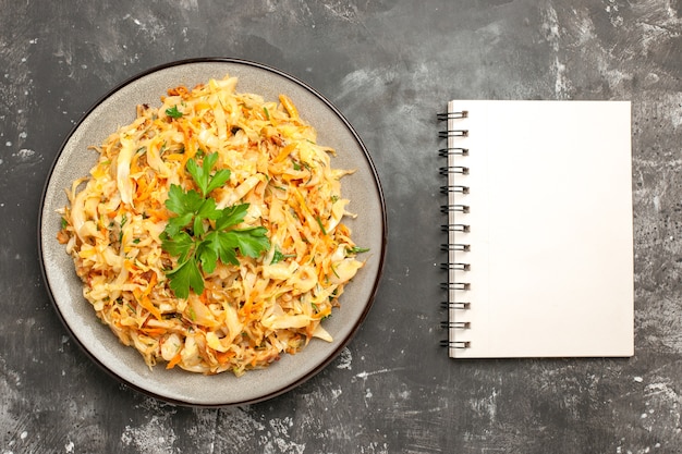 Top vista ravvicinata cavolo il cavolo appetitoso con taccuino bianco di erbe carote