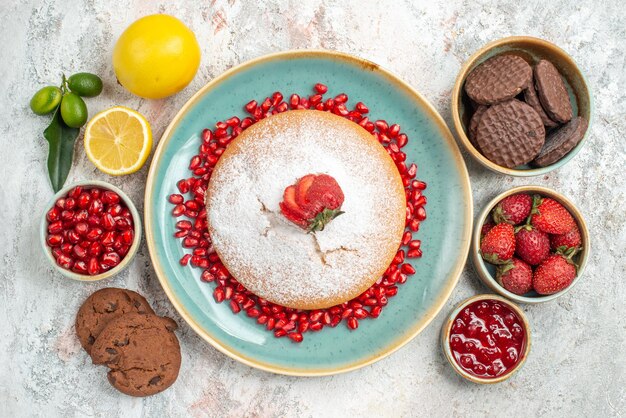 Top vista ravvicinata ciotole di biscotti al cioccolato bacche limone e torta con fragole