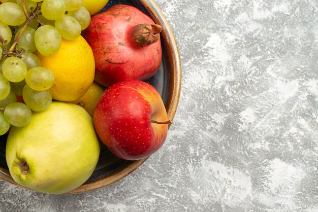 Top vista ravvicinata composizione di frutta fresca mele uva e altri frutti su sfondo bianco frutta fresca e pastosa colore maturo vitamina