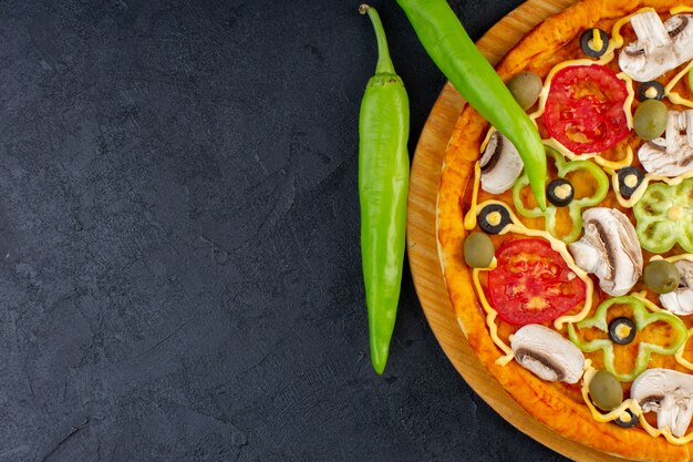 Top vista ravvicinata deliziosa pizza ai funghi con pomodori rossi peperoni olive e funghi tutti affettati all'interno sullo sfondo scuro cibo pizza italiana