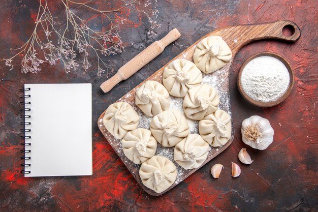 Top vista ravvicinata khinkali l'appetitoso khinkali sulla ciotola di aglio bordo del taccuino di farina