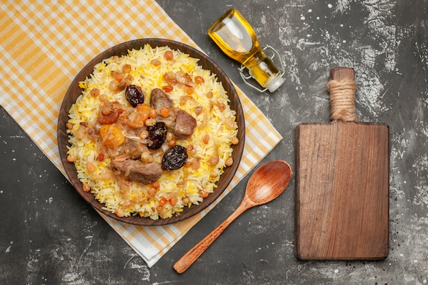 Top vista ravvicinata pilaf cucchiaio pilaf sulla tovaglia a scacchi la bottiglia di olio tagliere