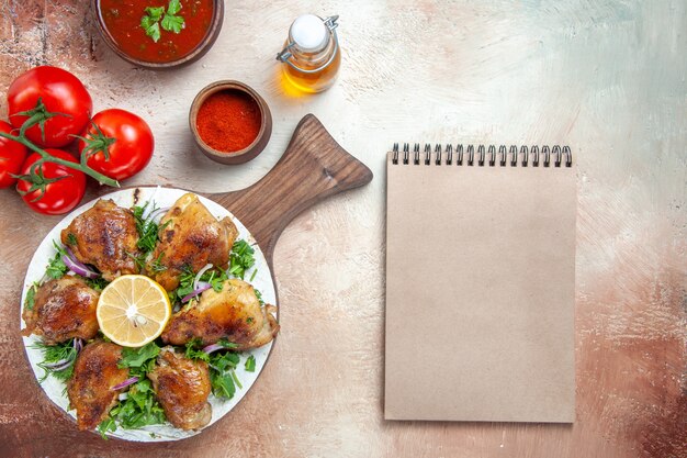 Top vista ravvicinata pollo pollo con erbe salsa di pomodori spezie bottiglia di taccuino di crema di olio