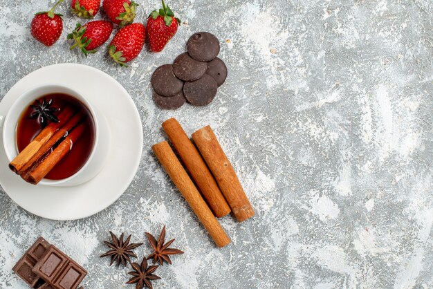 Top vista ravvicinata tè ai semi di anice cannella e alcune fragole cioccolatini cannellini semi di anice sul lato sinistro del tavolo con spazio libero