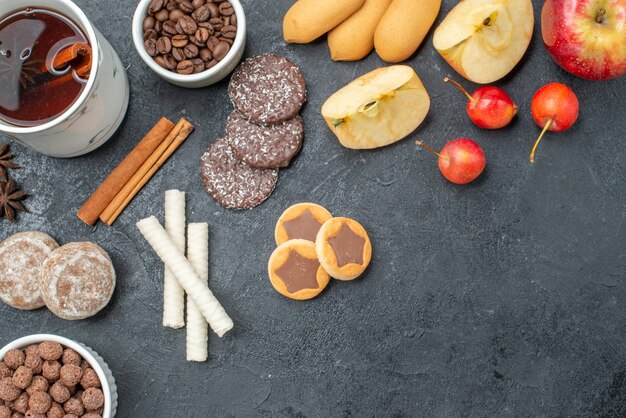 Top vista ravvicinata tè una tazza di tè anice stellato chicchi di caffè mele ciliegie biscotti