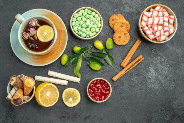 Top vista ravvicinata una tazza di tè biscotti una tazza di tè caramelle colorate marmellata limone cannella