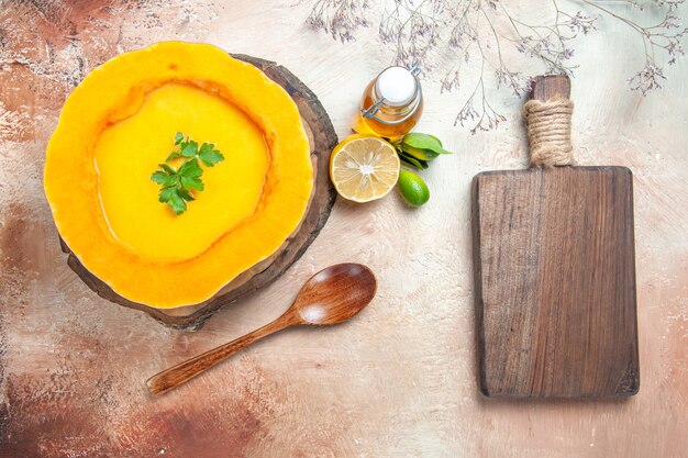 Top vista ravvicinata una zuppa di zucca minestra con erbe aromatiche sulla tavola cucchiaio olio limone il tagliere