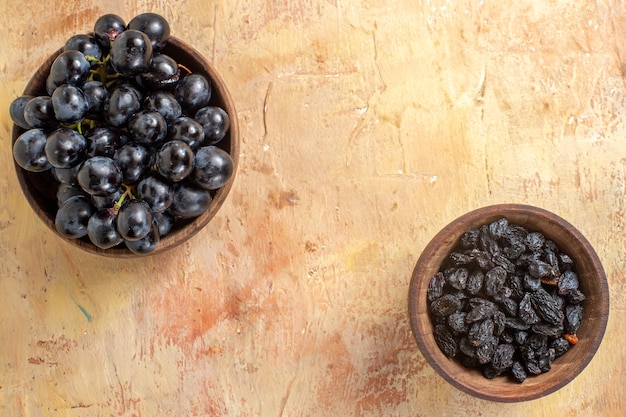 Top vista ravvicinata uva ciotole di uva nera e uvetta sul tavolo
