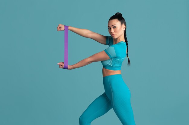 Torace. Bella giovane atleta femminile che si esercita in studio, ritratto blu monocromatico