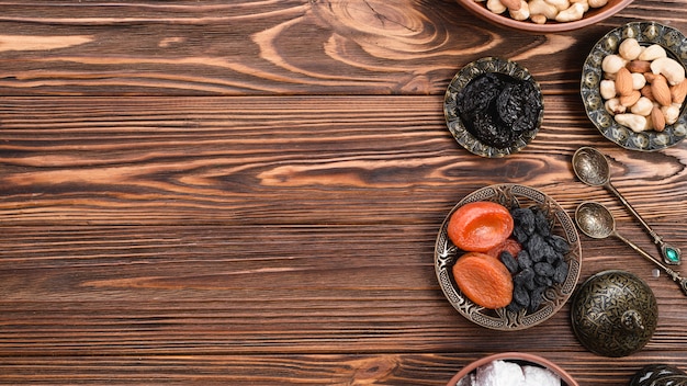 Toreutic ha inciso le ciotole metalliche artistiche con frutta secca e noci su superficie di legno