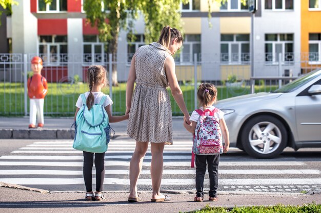 Torna al concetto di istruzione scolastica con bambine, studentesse elementari, portando zaini che vanno in classe