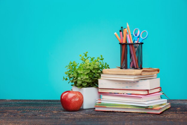 Torna al concetto di scuola. Libri, matite colorate e mela