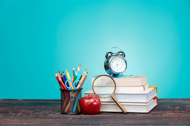 Torna al concetto di scuola. Libri, matite colorate e orologio