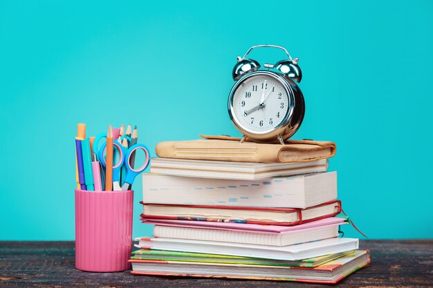 Torna al concetto di scuola. Libri, matite colorate e orologio