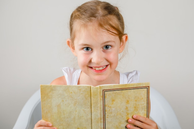 Torna al concetto di scuola vista laterale. ragazza seduta e tenendo il libro.