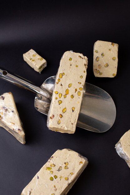 Torrone squisito di vista frontale affettato con le fette dell'arachide sul pavimento scuro