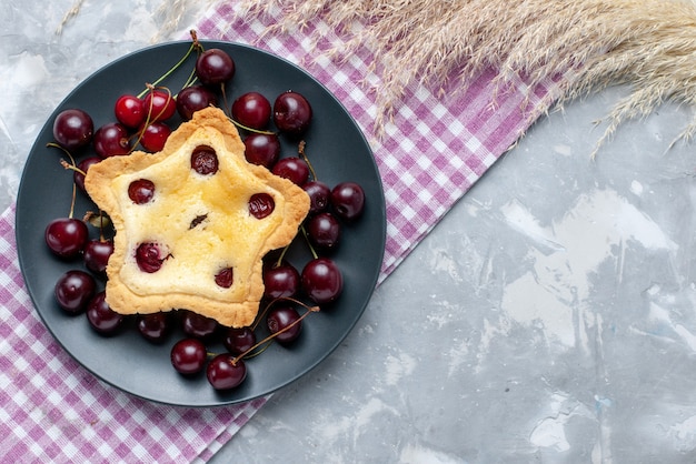 Torta a forma di stella vista dall'alto con amarene fresche all'interno della piastra sulla torta di frutta sfondo chiaro cuocere dolce