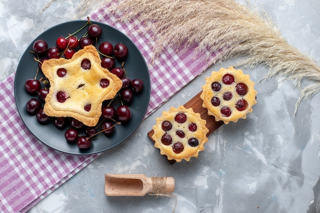 Torta a forma di stella vista dall'alto insieme a torte di ciliegie e amarene fresche sul tavolo leggero torta torta cuocere il colore della frutta