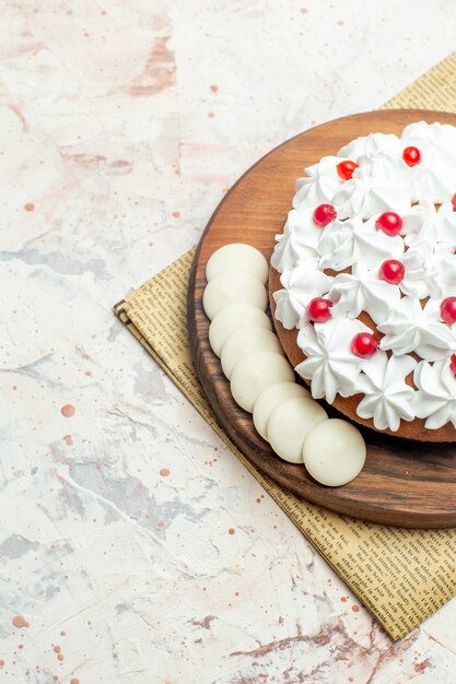 Torta a metà vista inferiore con crema pasticcera bianca su tavola di legno su giornale su superficie grigio chiaro