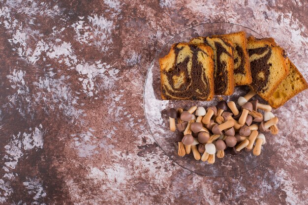 Torta al cacao a fette con biscotti in un piatto di vetro, vista dall'alto