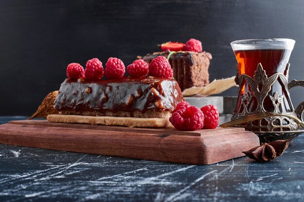 Torta al cioccolato con lamponi e un bicchiere di tè.