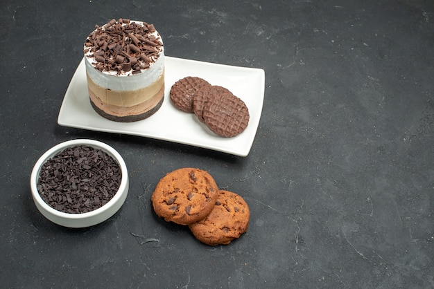 Torta al cioccolato e biscotti vista frontale su ciotola rettangolare bianca con biscotti al cioccolato fondente su fondo scuro