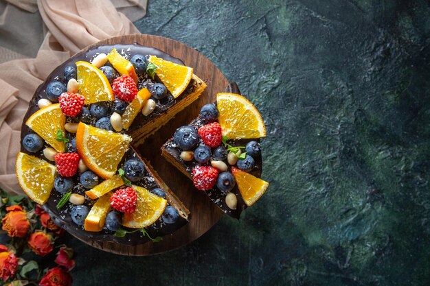 Torta al cioccolato gustosa vista dall'alto con frutta su fondo scuro