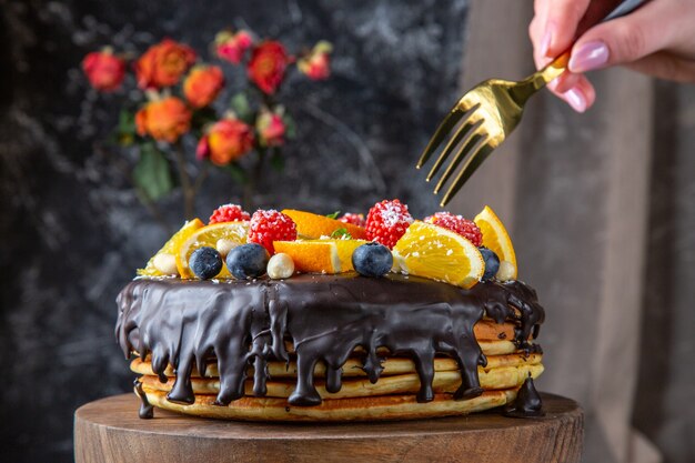 Torta al cioccolato gustosa vista frontale con frutta fresca sulla parete scura