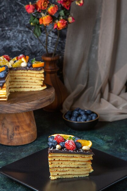 Torta al cioccolato gustosa vista frontale con frutta sulla parete scura