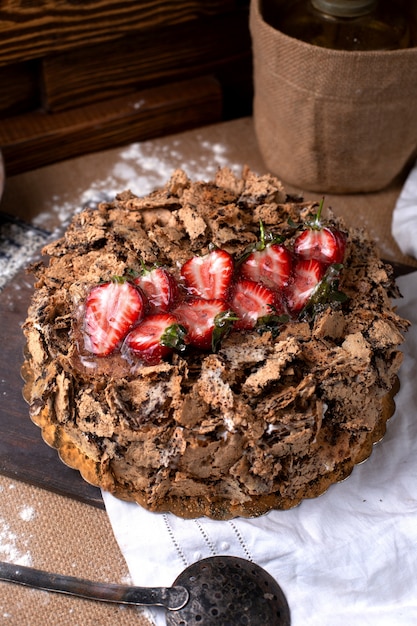 Torta al cioccolato vista frontale con fragole fresche rosse sulla superficie marrone