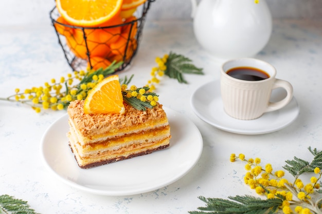 Torta arancione decorata con fette d'arancia fresche e fiori di mimosa sulla luce