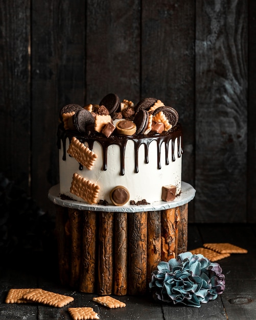 Torta bianca versata con cioccolato e decorata con diversi biscotti