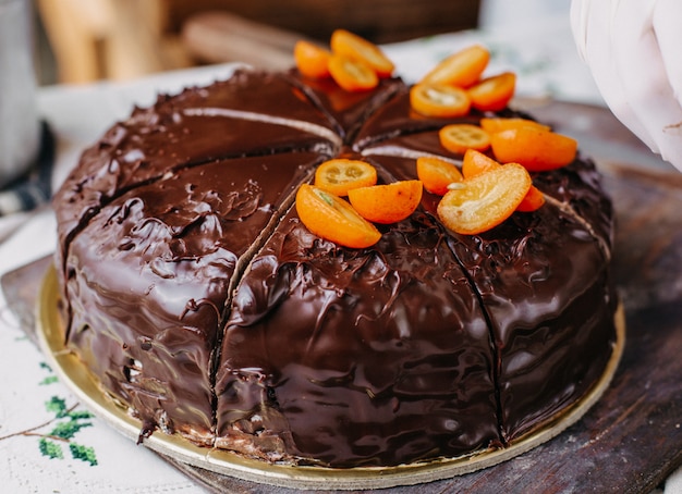 torta choco che viene tagliata squisita deliziosa rotonda intera progettazione con noci kumquat